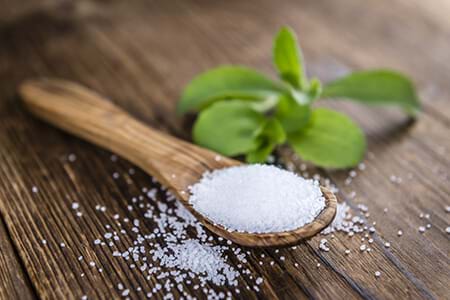The stevia plant and sweeteners granules on a wooden surface. stevia plant and sweetener on wood
