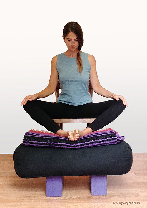 Bound angle yoga pose can be modified for people with limited mobility. woman doing bound angle yoga pose modification in chair