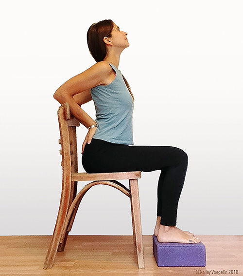 Camel pose in yoga can be modified for people with limited mobility. woman doing camel yoga pose modification in chair