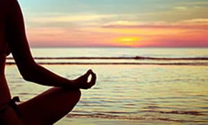 A woman meditating on the beach during sunset. woman meditating on beach