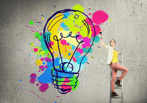 Daydreaming helps us come up with more creative ideas. woman on ladder creating a big colorful lightbulb as an idea